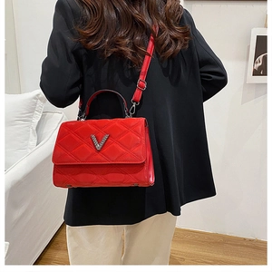 Détail du sac à main en cuir verni rouge matelassé avec logo en V sur blazer noir