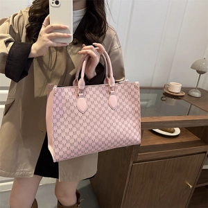 Grand sac cabas rose avec imprimé monogramme M porté par un mannequin chic