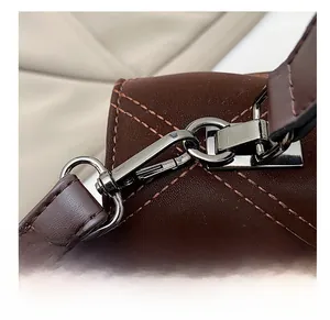 Détail du crochet métallique et de la couture matelassée du sac à main marron