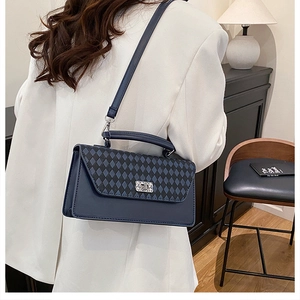 Detail einer dunkelblauen gesteppten Handtasche mit silbernem Strassverschluss und Griff