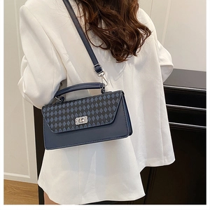 Details einer blauen Stepptasche mit silberner Kristallschnalle auf weißem Blazer