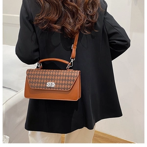 Schicke Retro-Umhängetasche mit braunem Rautenmuster an Model mit schwarzem Blazer