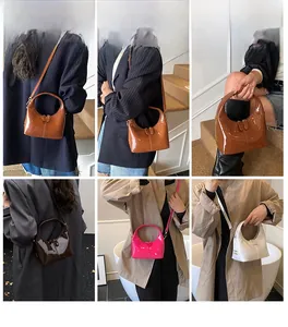 Dettaglio borsa a mano lucida in marrone, rosa e bianco indossata a tracolla