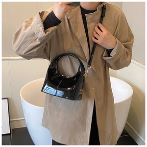 Dettaglio borsa hobo in vernice nera con tracolla regolabile e logo in metallo dorato