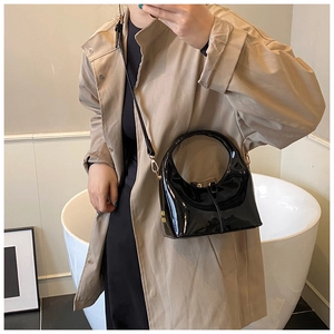 Dettaglio della borsa a mano nera lucida in vernice abbinata a un trench coat beige