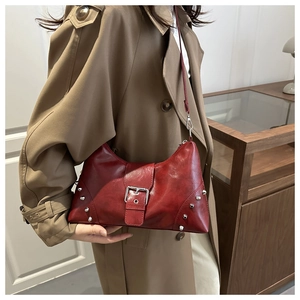 Schicke rote Tasche mit Nieten, getragen von einem Model im Trenchcoat