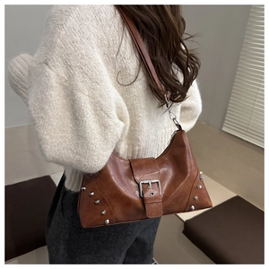 Detailed view of silver conical studs and metal buckle on brown punk style tote bag