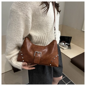 Detail of brown PU leather crescent bag with silver rivets and buckle in a lifestyle setting