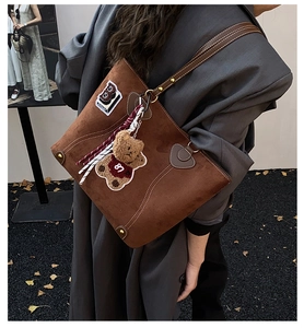 Detail der braunen matten Shopper Tasche mit B-Patch und Plüschbär-Anhänger