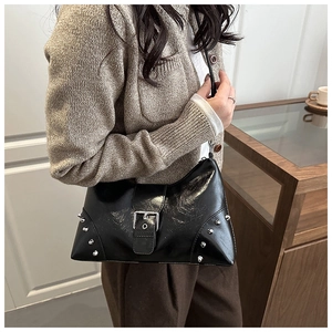 Detail der schwarzen Ledertasche mit Nieten und Schnallen an einem weiblichen Model