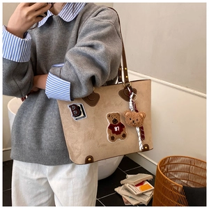 Seitenansicht beige Shopper Tasche mit Bären-Patch und braunen Lederriemen am Model
