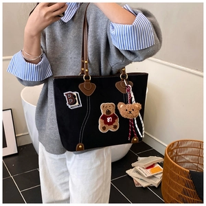 Detailansicht der schwarzen Segeltuchtasche mit Bärenstickerei und braunen Ledergriffen