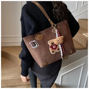Detail der braunen Wildledertasche mit Bärenstickerei und Plüsch-Anhänger-Anhänger