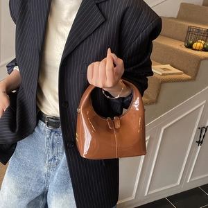 Borsa a mano in vernice lucida marrone con finiture dorate in un contesto lifestyle