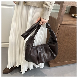 Detail of a deep brown pleated PU leather cloud bag showing soft lychee grain texture