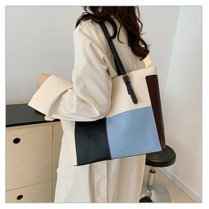 Detail view of large color-block tote bag on model showing stylish PU leather patchwork