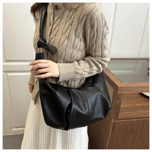 Detail of black large capacity shoulder bag with lychee texture and knot decoration