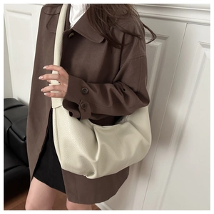 Detailed view of cream pleated hobo bag texture and wide strap on a model