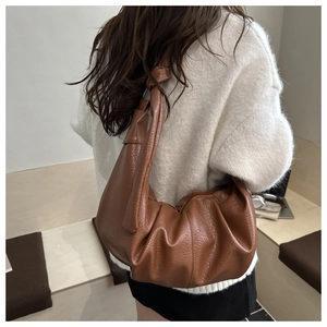 Detail view of brown hobo bag showing litchi texture and stylish knotted shoulder strap