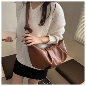 Detailed view of brown ruched cloud bag showing lychee grain leather and knotted strap