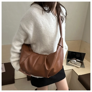 Detail view of brown pleated crescent bag featuring lychee texture and soft PU leather