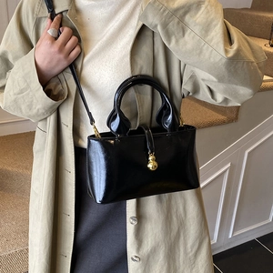 Glossy black patent leather bucket bag with gold gourd charm and adjustable shoulder strap