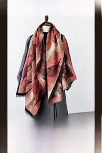 Detail of warm imitation cashmere scarf with red and beige feather print and soft tassels