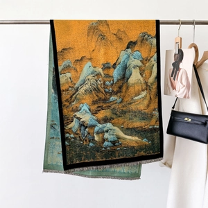 Chinese landscape art scarf in yellow and green with tassels hanging on a wall