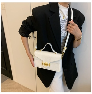 Détail du sac blanc à texture serpent avec boucle en métal doré et lettre M
