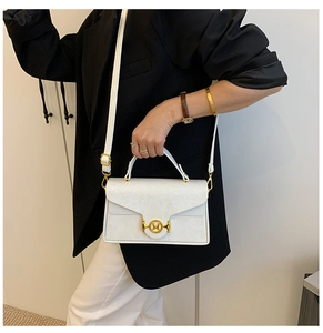 Détail du sac à main blanc motif serpent avec fermoir doré M sur blazer noir chic