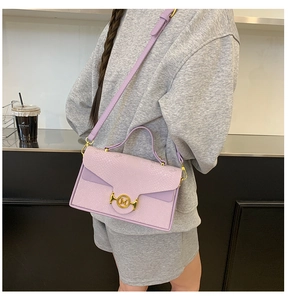 Gros plan du sac lilas en cuir effet serpent avec boucle dorée M porté par un mannequin