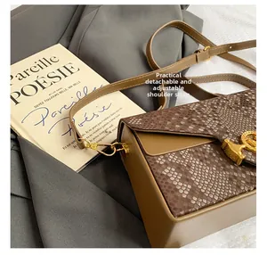 Détail d'un sac marron motif serpent avec bandoulière réglable et fermoir doré en H