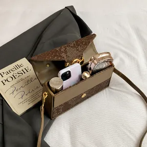 Détail de la texture serpent sur le sac à bandoulière avec intérieur pour maquillage