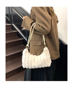 Detail of cream plush tote bag with vertical stripes and woven cord strap in warm setting
