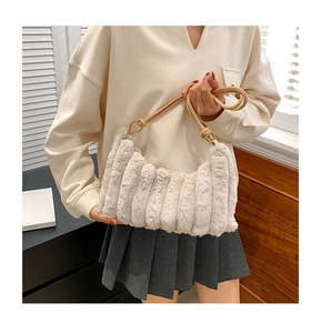 Λεπτομέρεια κρεμ τσάντας από συνθετική γούνα με κάθετες πιέτες και καφέ λουράκι ώμου