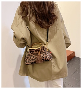 Détail du sac léopard avec fermoir en métal doré et pompon marron sur une bandoulière