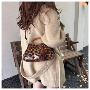Détail du sac léopard avec poignée en bois et pompon sur un manteau en laine beige