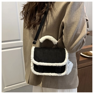 Detail of suede saddle bag with faux fur trim, adjustable strap and plush charm