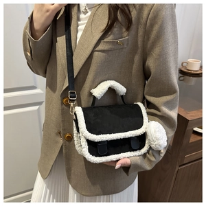 Detail of crossbody bag with black matte texture and white faux shearling trim accents