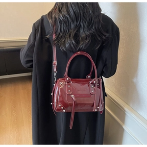 Detail of burgundy leather tote bag with silver studs and long tassels on crossbody strap