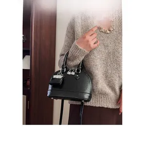 Détail du sac à main noir en forme de coquille avec petit porte-monnaie et bandoulière