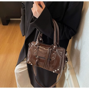 Close-up of dark brown glossy pillow bag featuring silver studs and long fringe tassels