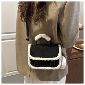 Detail of wool-trimmed saddle bag worn cross-body over a brown blazer and white skirt