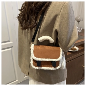 Detail of a brown suede crossbody bag with white faux fur trim and plush round charm