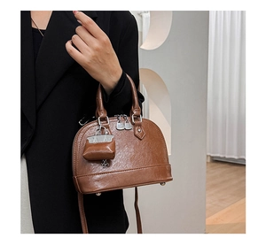 Vue détaillée d'un sac à main marron avec texture plissée et mini bijou de sac