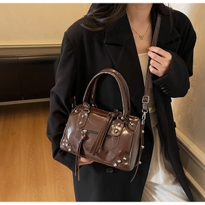 Detail of dark brown leather Boston bag featuring rivets, tassels and silver hardware