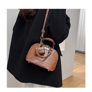 Sac à main marron en cuir avec mini porte-monnaie porté avec un costume noir chic