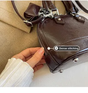 Détail macro des coutures précises et des rivets argentés sur le sac marron foncé