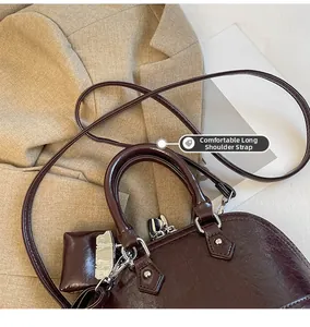 Détail du sac coquillage bordeaux avec cuir brillant et une longue bandoulière réglable