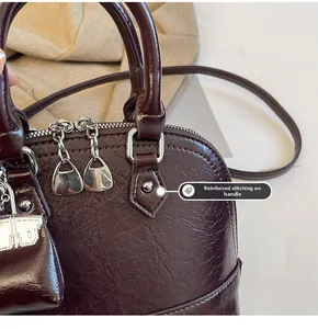 Gros plan des coutures renforcées sur un sac à main en cuir grainé bordeaux